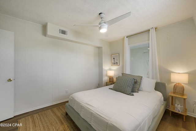 bedroom with ceiling fan, dark hardwood / wood-style flooring, and a textured ceiling