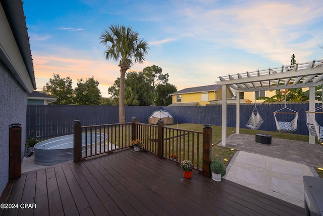 deck at dusk featuring a lawn and a patio