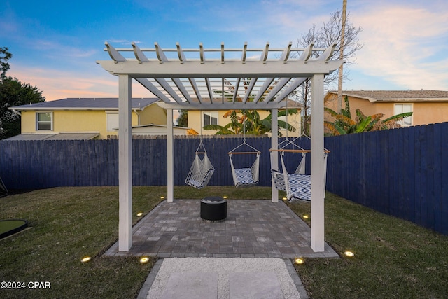 patio terrace at dusk featuring a pergola and a yard