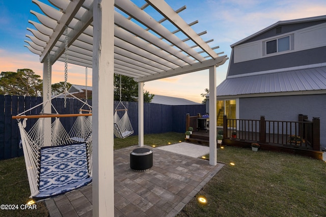 patio terrace at dusk featuring a yard and a pergola