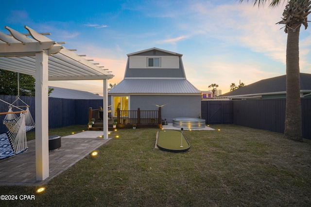 back house at dusk with a pergola, a patio area, and a yard