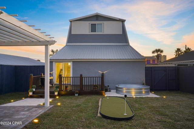 back house at dusk featuring a pergola, a patio, and a lawn