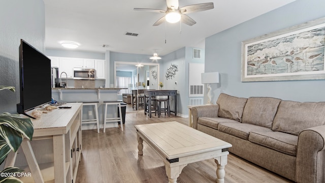 living room featuring light hardwood / wood-style flooring and ceiling fan