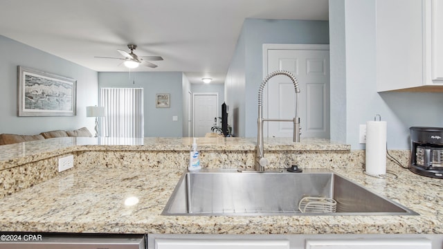 kitchen with light stone counters, sink, white cabinetry, ceiling fan, and stainless steel dishwasher