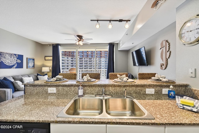 kitchen featuring open floor plan, dishwashing machine, a textured ceiling, and a sink