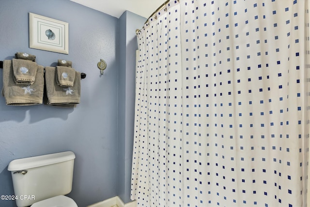 bathroom with curtained shower and toilet