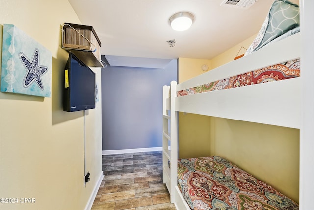 bedroom featuring wood finished floors, visible vents, and baseboards