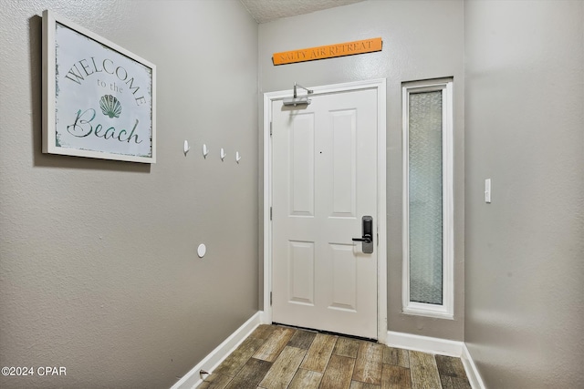 doorway to outside featuring baseboards and wood finish floors