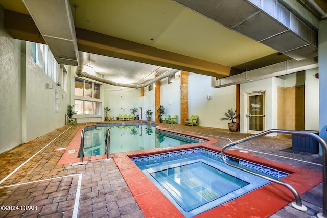 community pool with an indoor hot tub and a patio