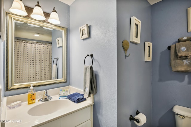 bathroom featuring curtained shower, vanity, and toilet