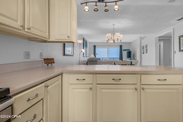 kitchen with a textured ceiling, cream cabinetry, a chandelier, and kitchen peninsula