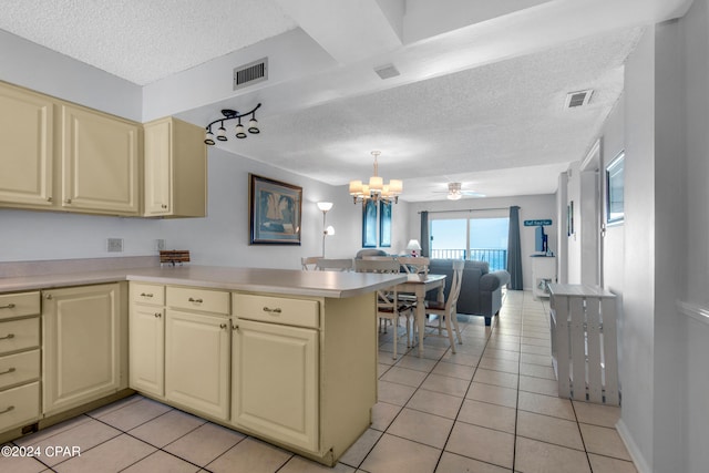 kitchen featuring cream cabinets, light tile patterned flooring, ceiling fan with notable chandelier, and kitchen peninsula