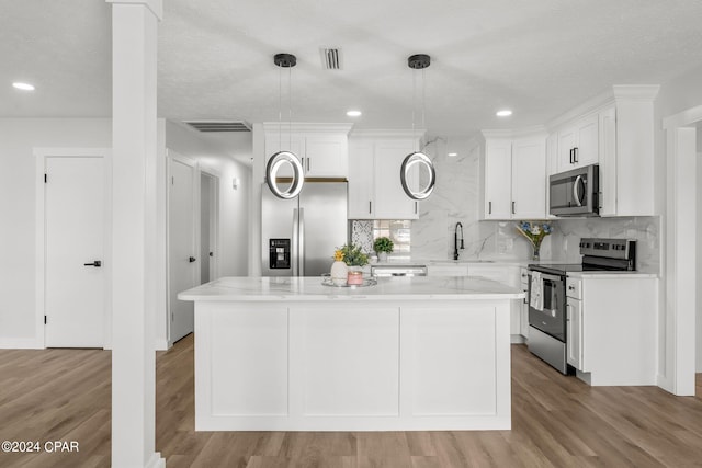 kitchen with pendant lighting, a kitchen island, stainless steel appliances, and light wood-type flooring