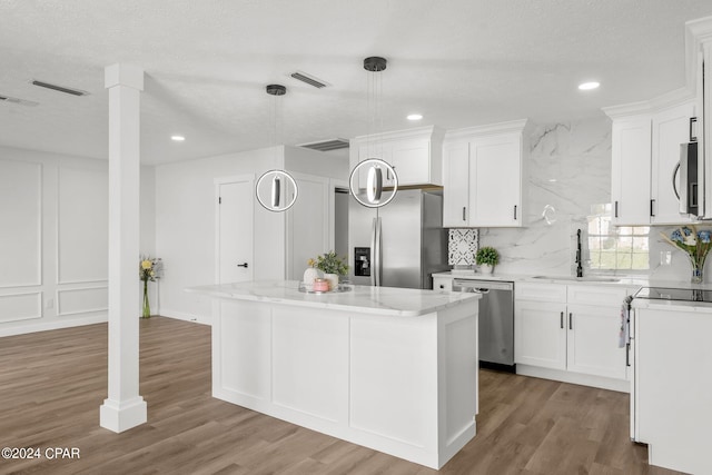 kitchen featuring white cabinets, stainless steel appliances, sink, and a kitchen island