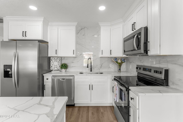 kitchen with light stone countertops, sink, appliances with stainless steel finishes, and white cabinetry