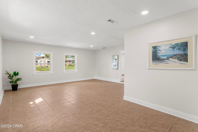 spare room with a textured ceiling and light tile patterned floors