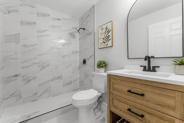 bathroom with vanity, toilet, and tiled shower