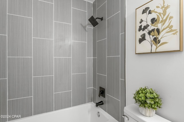 bathroom featuring tiled shower / bath combo and toilet