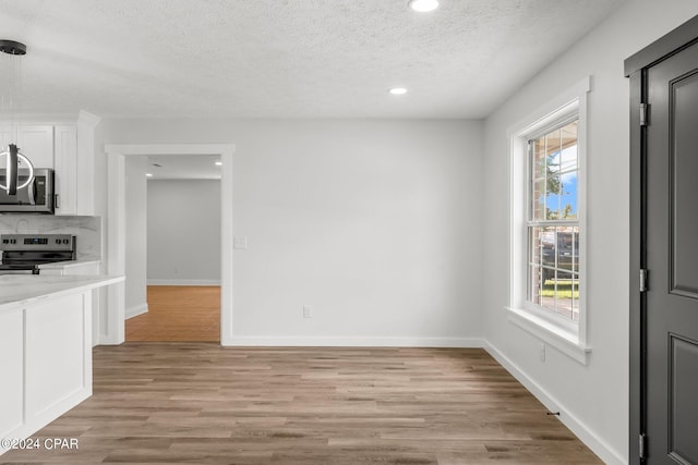 unfurnished dining area featuring light hardwood / wood-style flooring and a textured ceiling