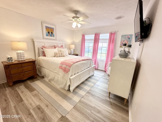 bedroom featuring a textured ceiling, baseboards, light wood-style flooring, and a ceiling fan