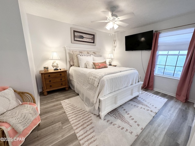 bedroom featuring a textured ceiling, ceiling fan, wood finished floors, and baseboards