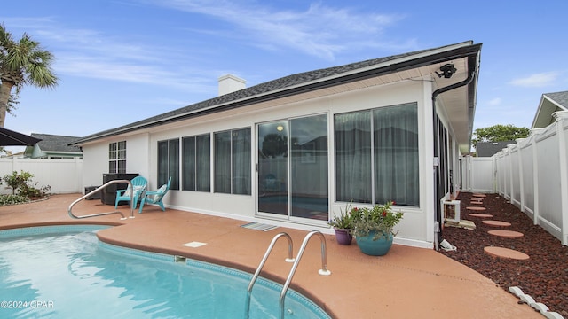 rear view of property with a fenced backyard, a chimney, a fenced in pool, and a patio