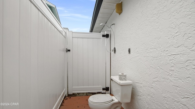 bathroom featuring toilet and a textured wall