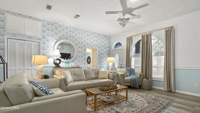 living room with baseboards, wood finished floors, visible vents, and wallpapered walls