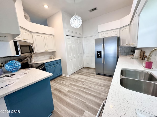 kitchen featuring visible vents, light wood-style flooring, appliances with stainless steel finishes, a sink, and blue cabinets