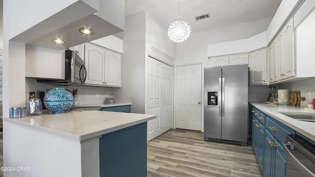 kitchen with stainless steel appliances, visible vents, blue cabinetry, backsplash, and light wood finished floors