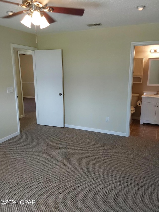 unfurnished bedroom featuring sink, ensuite bathroom, ceiling fan, and carpet