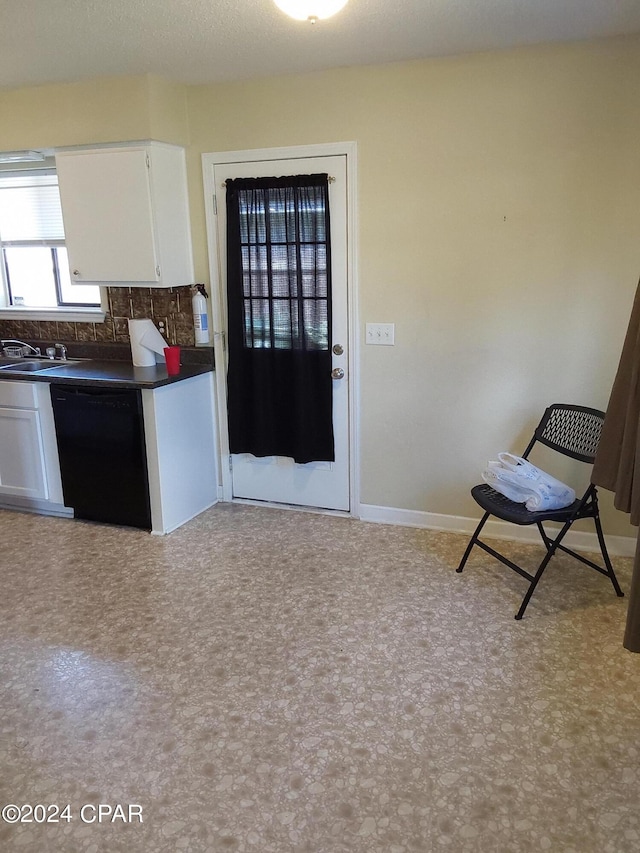 kitchen with white cabinets, black dishwasher, decorative backsplash, and sink