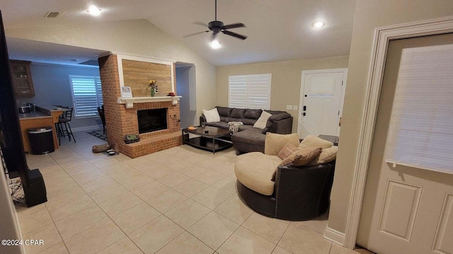 tiled living room featuring a brick fireplace, ceiling fan, and vaulted ceiling