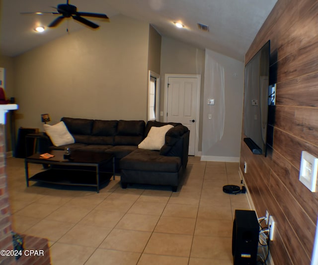 living room with wood walls, ceiling fan, vaulted ceiling, and light tile patterned floors