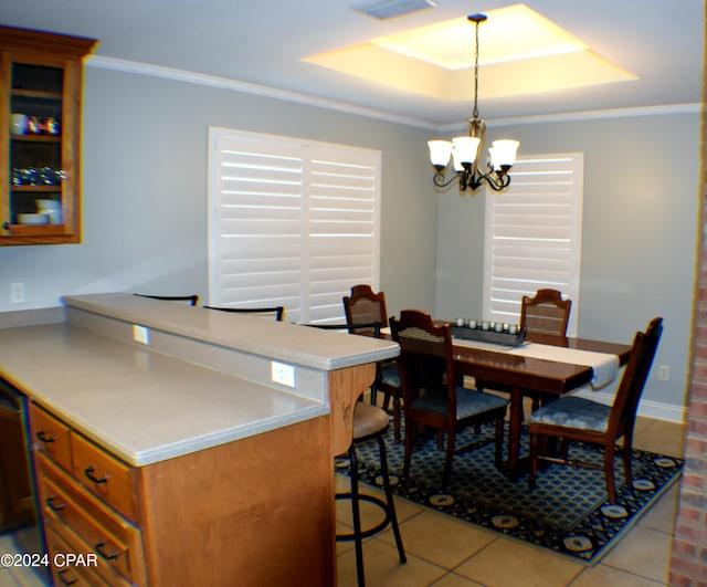 tiled dining area featuring a raised ceiling, crown molding, and a notable chandelier