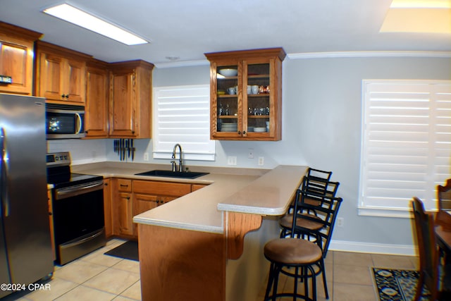 kitchen featuring sink, appliances with stainless steel finishes, ornamental molding, a kitchen bar, and light tile patterned floors