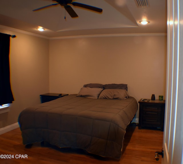 bedroom featuring wood-type flooring, ceiling fan, crown molding, and a tray ceiling