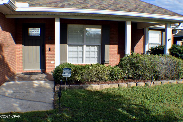 property entrance with a porch and a lawn