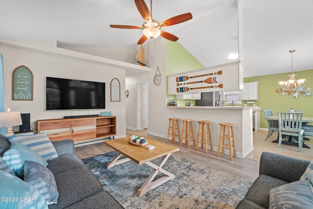 living room with ceiling fan with notable chandelier, high vaulted ceiling, and light hardwood / wood-style flooring