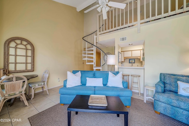 tiled living room with ceiling fan and a towering ceiling