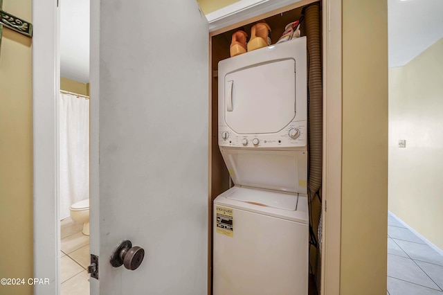 washroom with stacked washer / dryer and light tile patterned floors