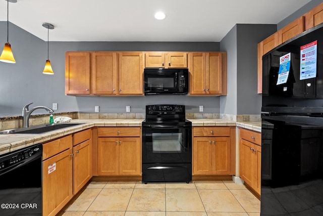 kitchen featuring decorative light fixtures, black appliances, sink, and light tile patterned floors