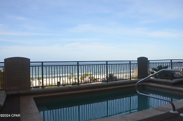 view of swimming pool featuring a view of the beach and a water view