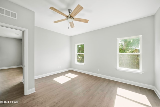 unfurnished room featuring hardwood / wood-style floors, a healthy amount of sunlight, and ceiling fan