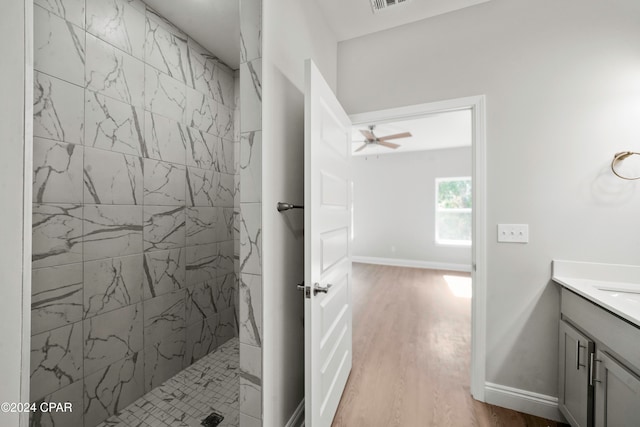 bathroom featuring tiled shower, vanity, hardwood / wood-style floors, and ceiling fan