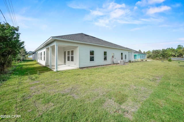 back of property with central AC unit, a yard, and a patio area