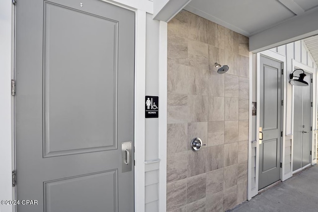 bathroom with concrete flooring and a tile shower