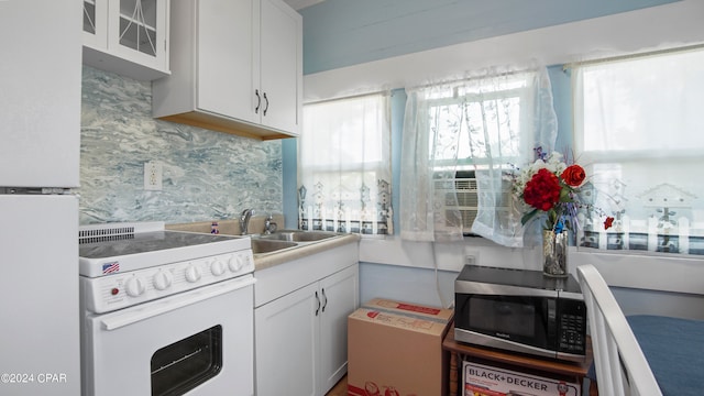 kitchen featuring backsplash, white appliances, sink, and white cabinets