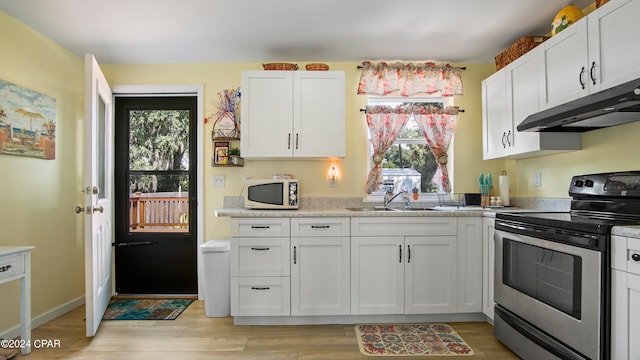 kitchen with stainless steel range with electric stovetop, light wood-type flooring, sink, and white cabinetry