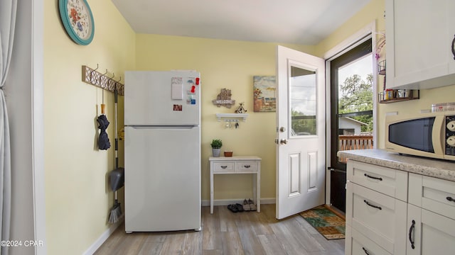 kitchen featuring light wood-type flooring, white appliances, and white cabinets